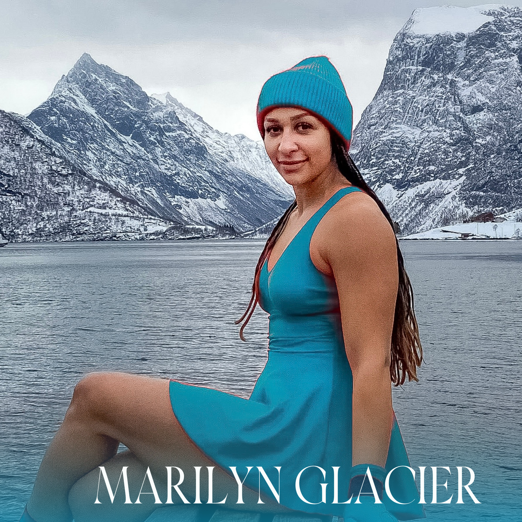 Dame som sitter på en brygge og har på seg Marilyn - Fjord Vibes badekjole Glacier i turkis farge med matchende lue i ull og neopren-badehansker