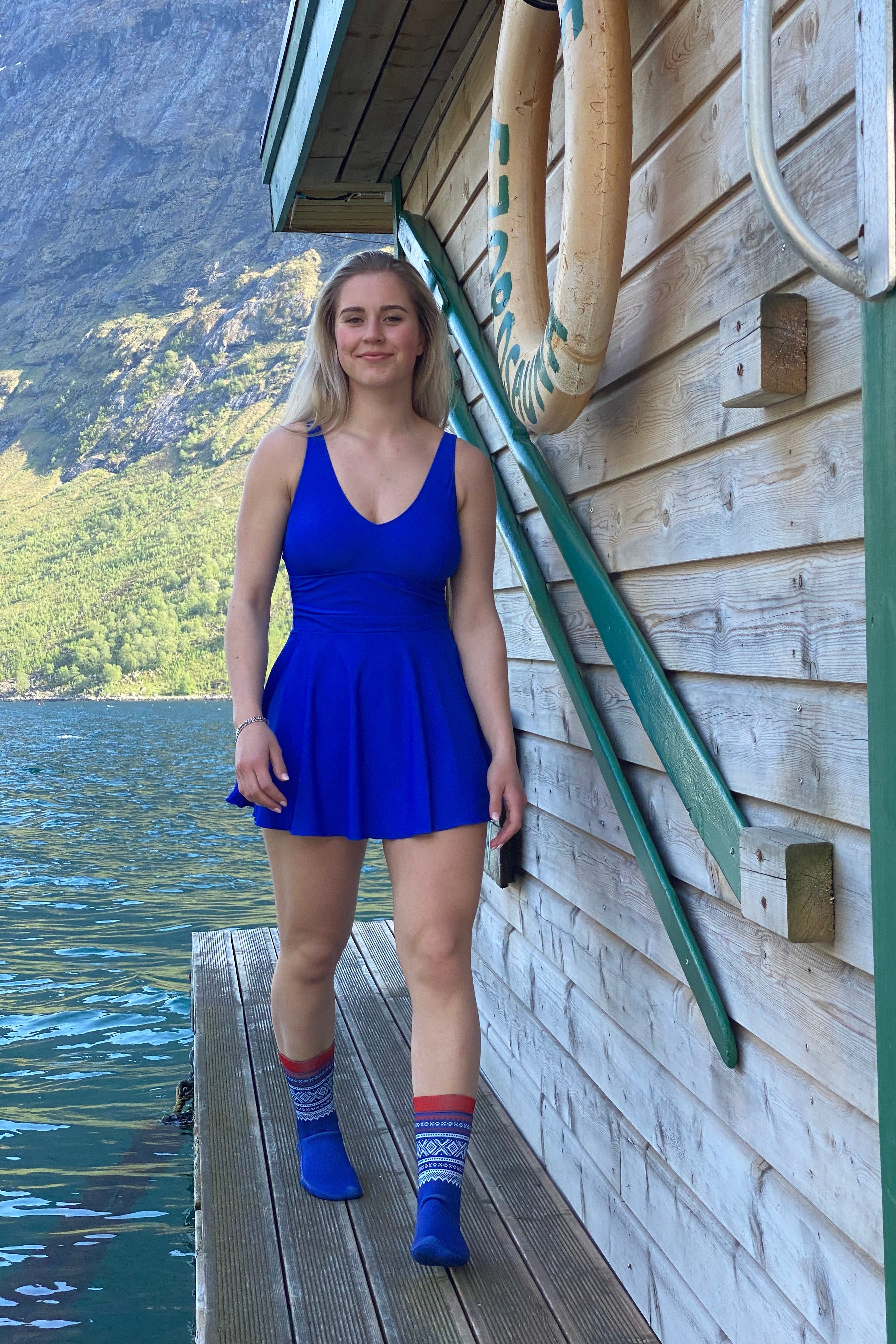 Marius®  Originale Neoprene Socks - DoUdare dame som har på matchende blå kjole går på en brygge ved en norsk fjord