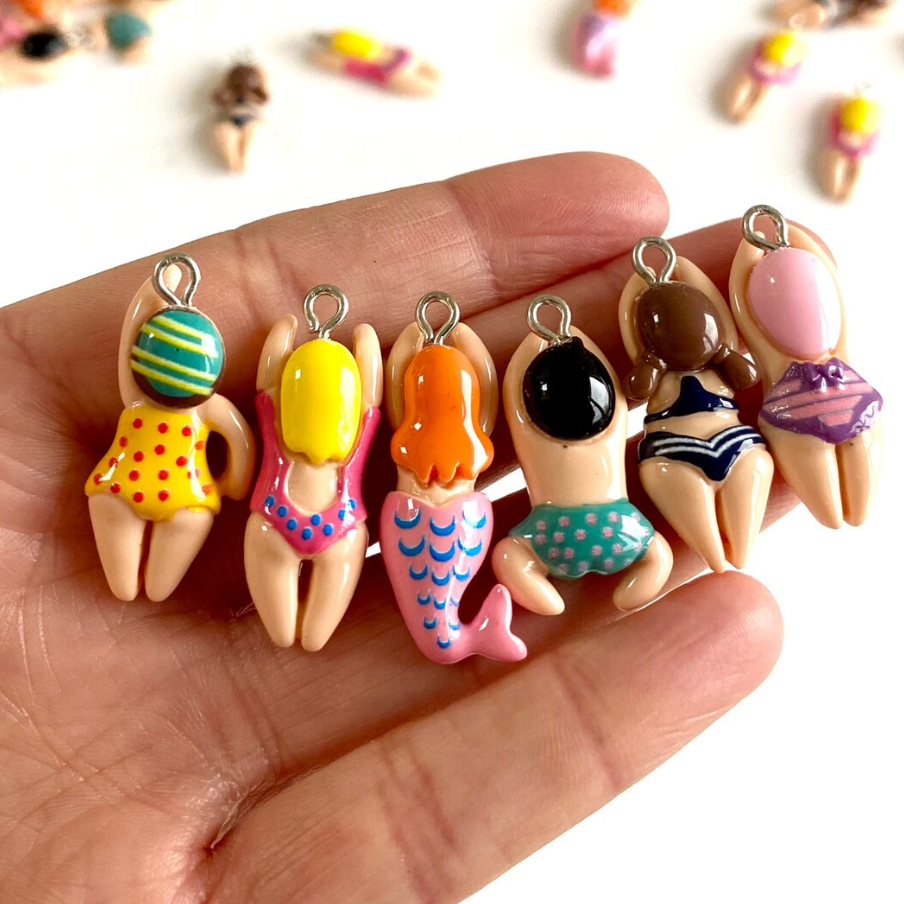 bilde av en hånd som holder 6 ulike badende charms-figurer til å henge på nøkkelring