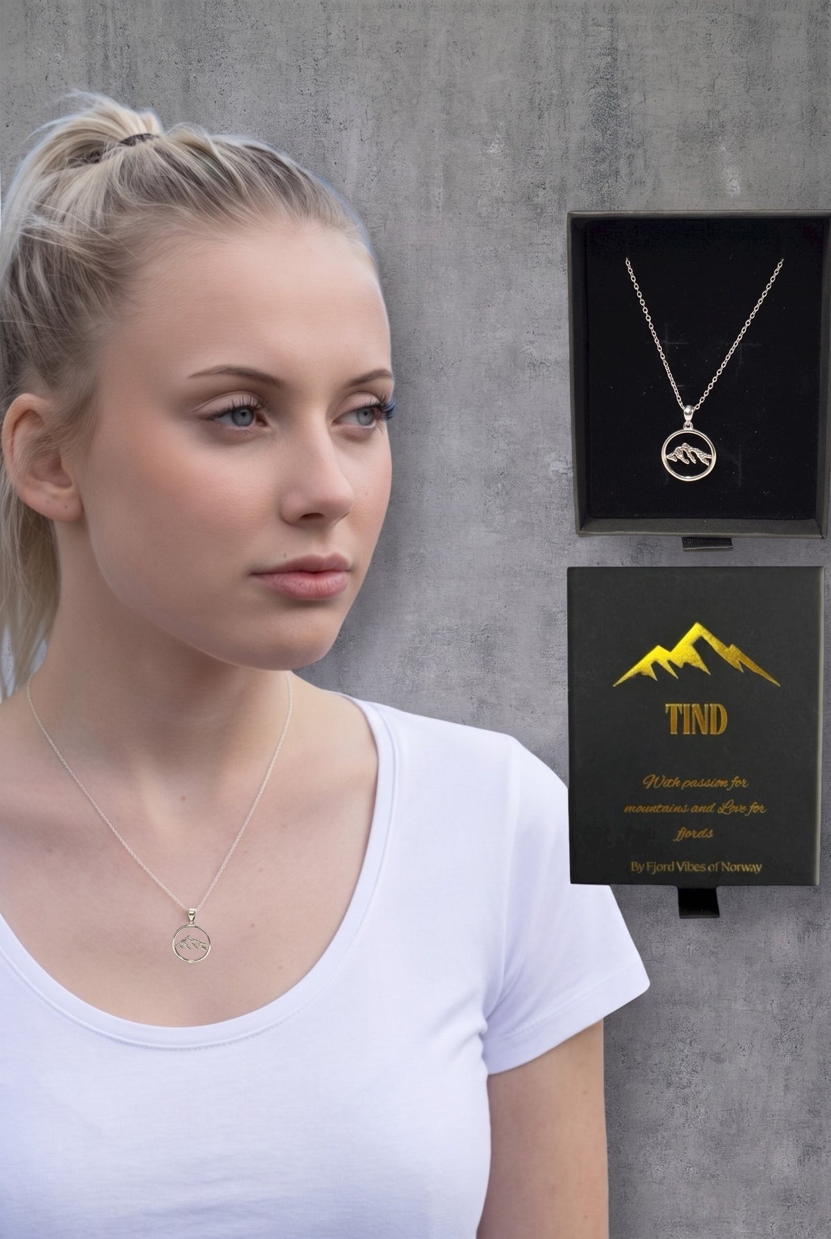 Kvinne med Tind fjellsmykke fra Fjord Vibes rundt halsen, ved siden av den svarte gaveesken med Tind-logo